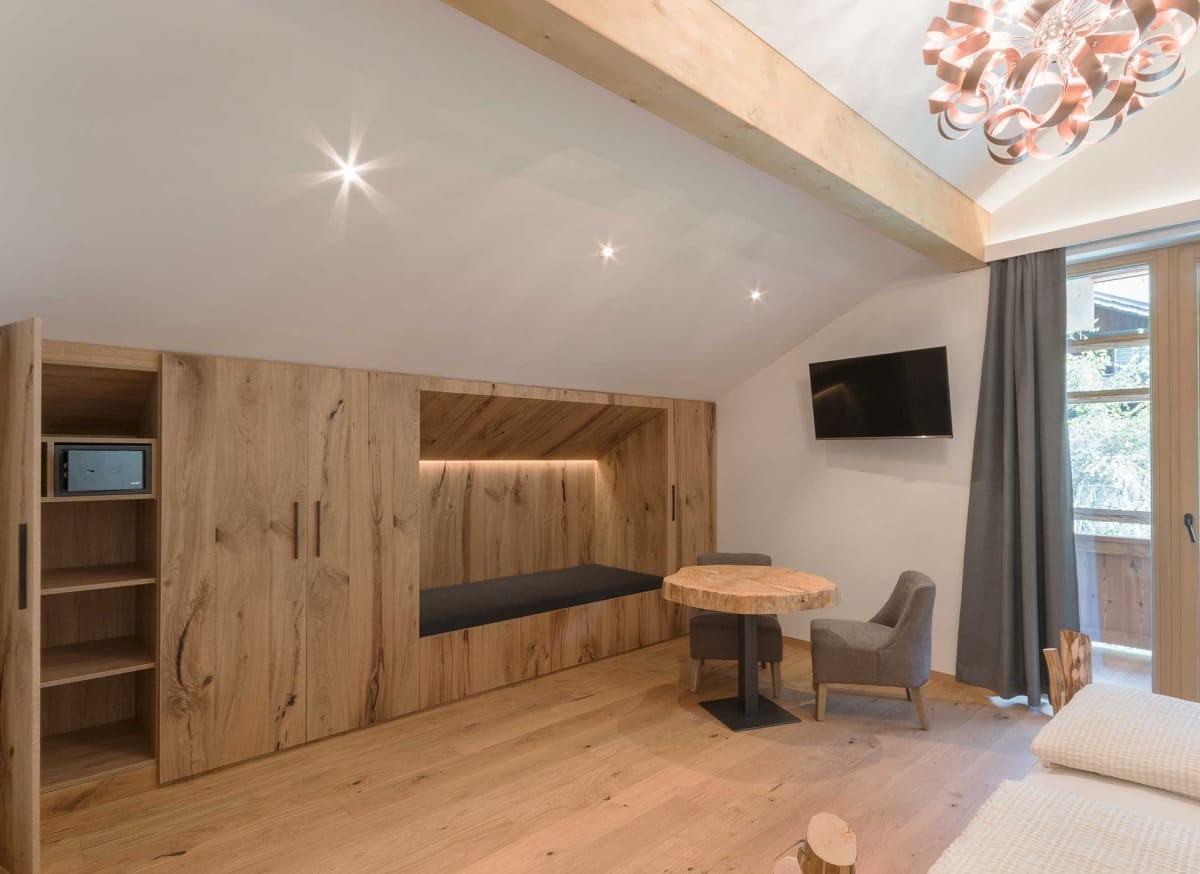 Komfortables Gästezimmer im Atelier Garni Astei Großarl mit Fernseher und moderner Holzeinrichtung