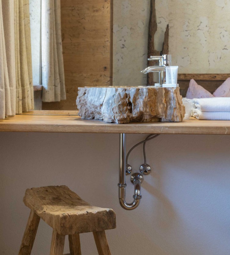 Badezimmer im Atelier Garni Astei Großarl mit Naturstein-Waschbecken und rustikalem Hocker
